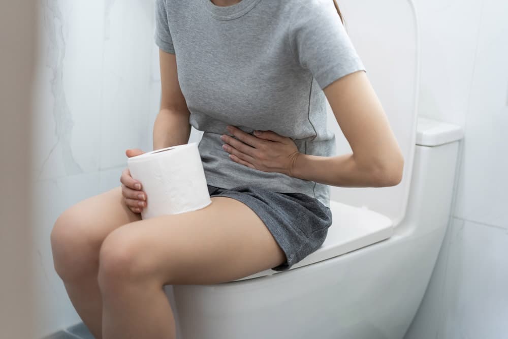 Woman sitting on the toilet with stomach discomfort.
